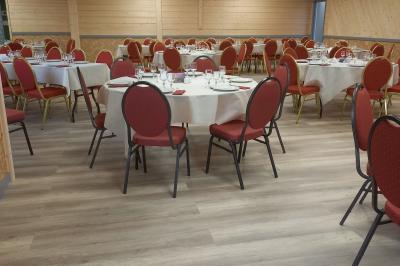 Chambre simple avec un lit double, une table en bois, une chaise et une lumière murale, donnant sur une porte vitrée.