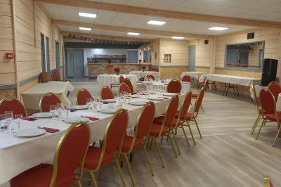 Chambre simple avec un lit double, une table en bois, une chaise et une lumière murale, donnant sur une porte vitrée.