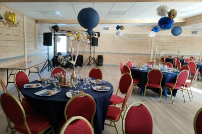 Chambre simple avec un lit double, une table en bois, une chaise et une lumière murale, donnant sur une porte vitrée.