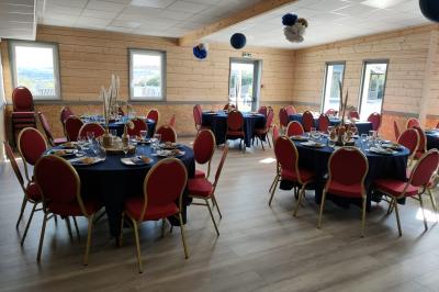 Chambre simple avec un lit double, une table en bois, une chaise et une lumière murale, donnant sur une porte vitrée.