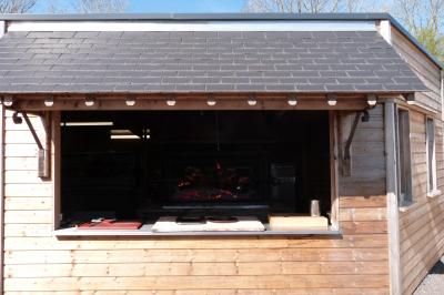 Chambre simple avec un lit double, une table en bois, une chaise et une lumière murale, donnant sur une porte vitrée.