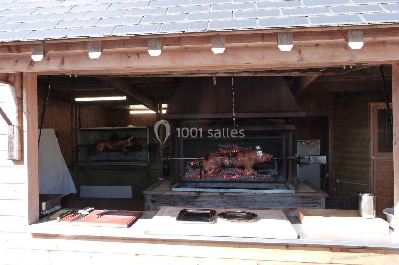 Un cochon rôti entier cuit à la broche sur un feu de bois dans un abri en bois ouvert.