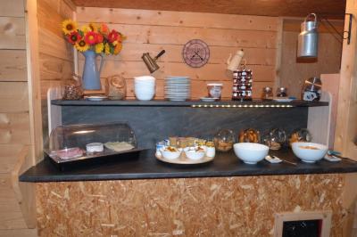 Chambre simple avec un lit double, une table en bois, une chaise et une lumière murale, donnant sur une porte vitrée.