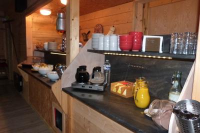 Chambre simple avec un lit double, une table en bois, une chaise et une lumière murale, donnant sur une porte vitrée.