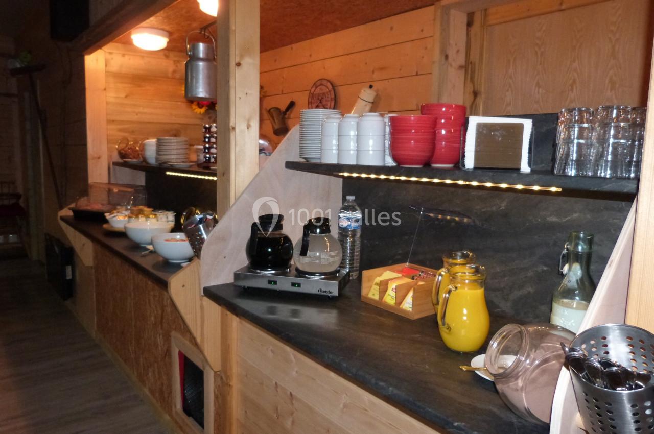 Buffet en bois avec boissons, vaisselle, carafes de jus et aliments disposés sur des étagères éclairées.