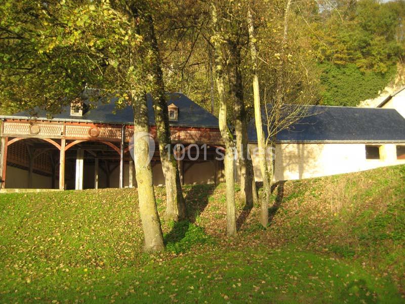 Bâtiment ancien avec toit en ardoise, entouré d'arbres et de pelouse, baigné par une lumière automnale.