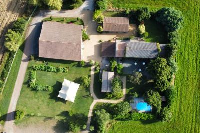 Vue aérienne d'une propriété rurale avec plusieurs bâtiments, une piscine, une tente blanche et des champs environnants.