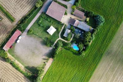 Vue aérienne d'une propriété rurale avec plusieurs bâtiments, une piscine, une tente blanche et des champs environnants.