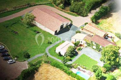Vue aérienne d'une propriété rurale avec plusieurs bâtiments, une piscine, une tente blanche et des champs environnants.