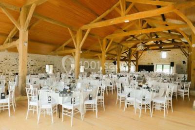 Espace salon lumineux avec fauteuils en osier, cheminée en pierre, piano, plantes et fenêtre donnant sur un jardin.