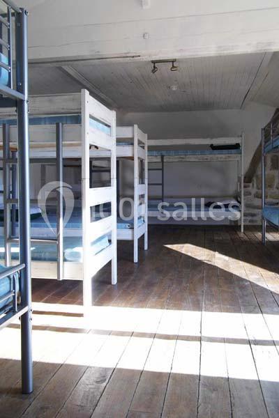 Dortoir lumineux avec lits superposés en bois et métal, sol en parquet et plafond en bois peint.