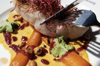 Une femme en tenue noire porte deux plateaux de hors-d'œuvre devant une porte rouge ouverte.