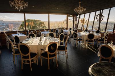 Une femme en tenue noire porte deux plateaux de hors-d'œuvre devant une porte rouge ouverte.