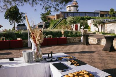 Une femme en tenue noire porte deux plateaux de hors-d'œuvre devant une porte rouge ouverte.
