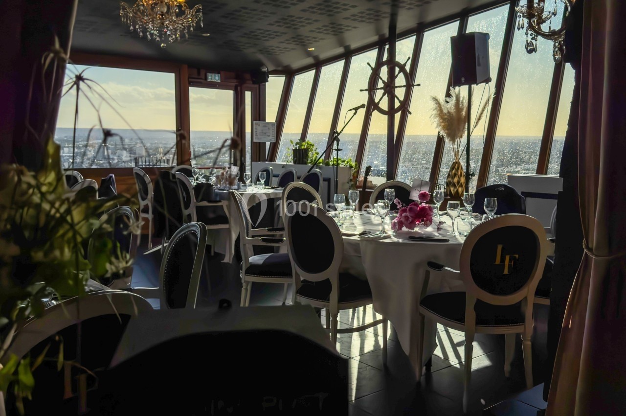 Salle de restaurant élégante avec vue panoramique sur la mer, tables dressées et lumière naturelle en fin de journée.