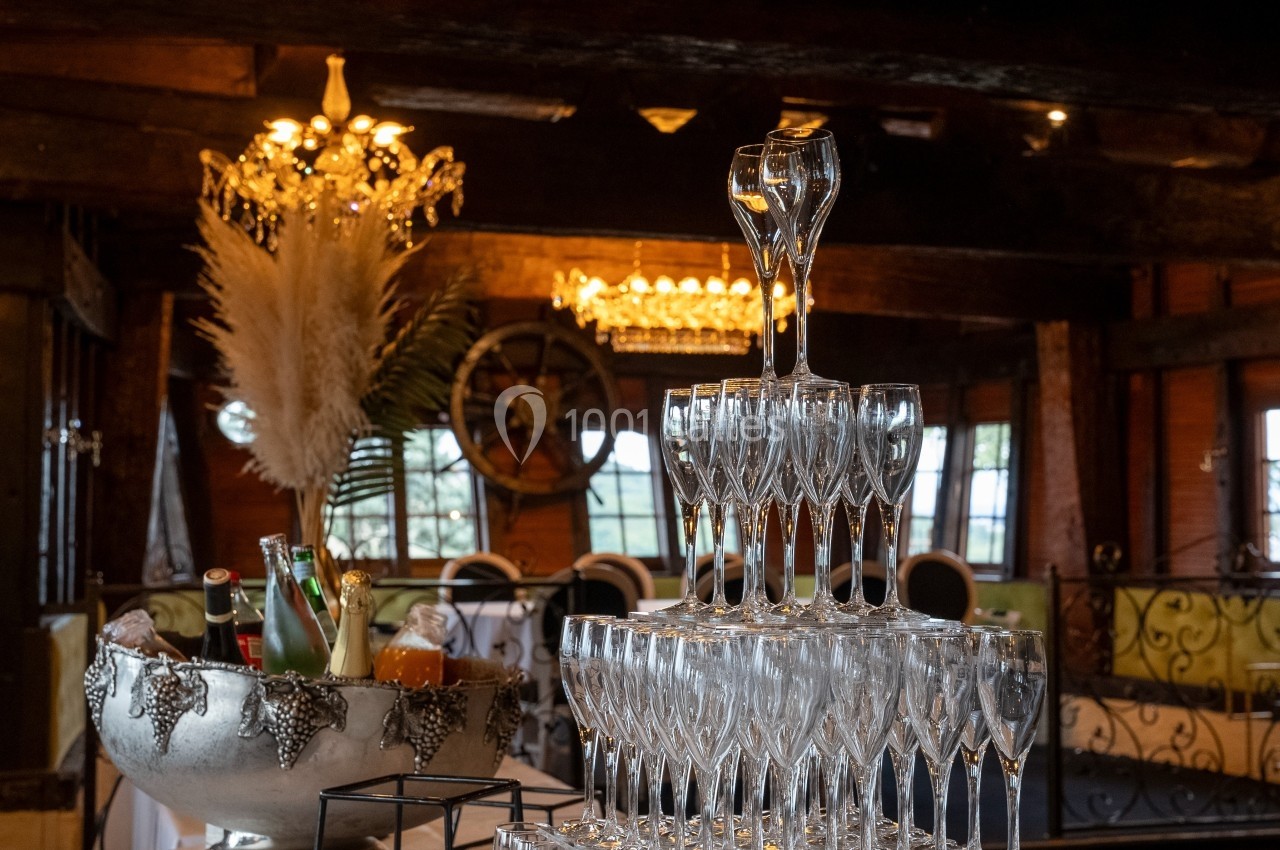 Pyramide de flûtes à champagne dans une salle décorée avec des chandeliers, des pampas et un seau à glace.
