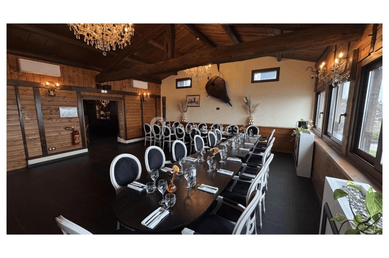 Salle de réception avec tables dressées, chaises noires et blanches, décor en bois et lustres suspendus.