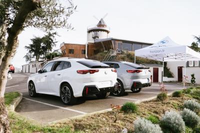 Personne coupant un plat composé de médaillons de viande, légumes rôtis et sauce blanche, servi sur une assiette blanche.