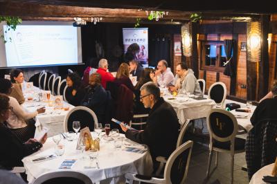 Personne coupant un plat composé de médaillons de viande, légumes rôtis et sauce blanche, servi sur une assiette blanche.
