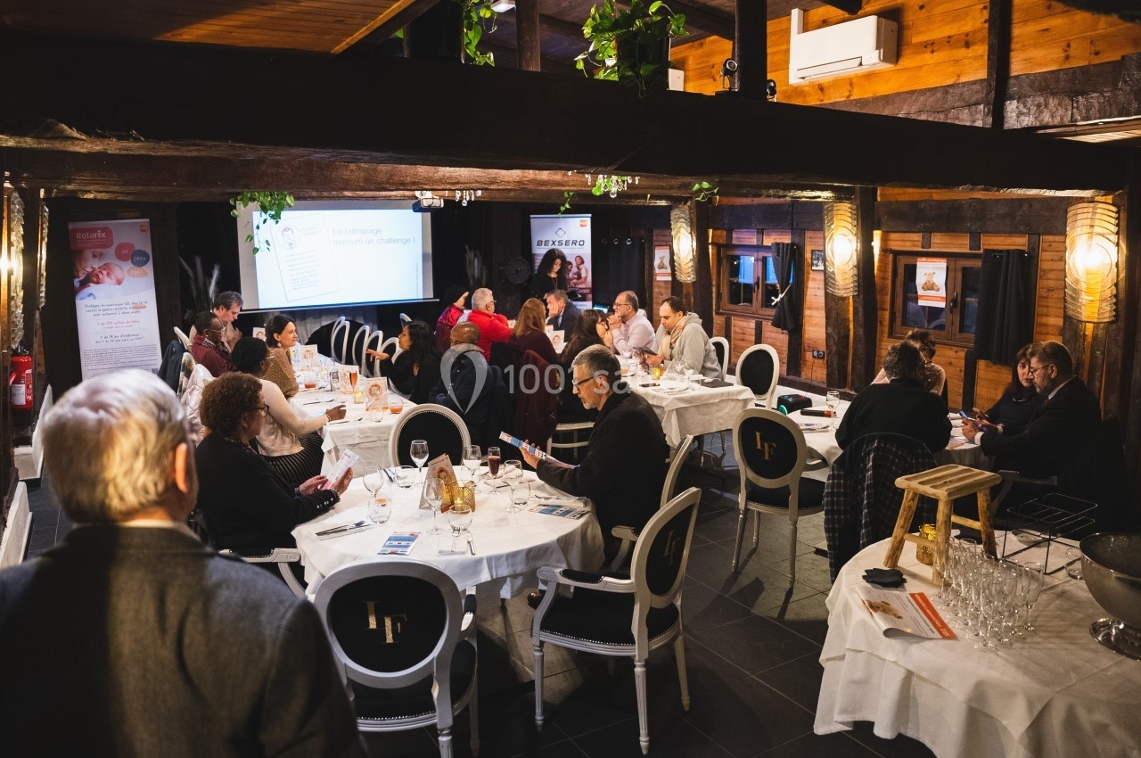 Des personnes assises autour de tables dans une salle en bois lors d'une réunion ou d'un événement professionnel.