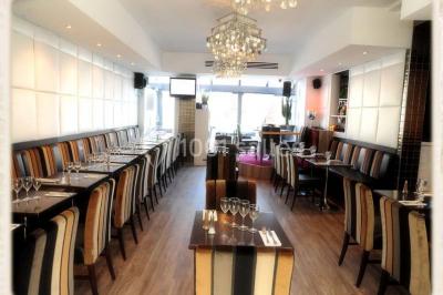 Miniature Location salle Rueil-Malmaison (Hauts-de-Seine) - Restaurant l'Avenue #6 Bar lumineux avec comptoir décoré de bouteilles colorées, entouré de tabourets et d'étagères garnies de bouteilles.