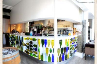 Miniature Location salle Rueil-Malmaison (Hauts-de-Seine) - Restaurant l'Avenue #9 Bar lumineux avec comptoir décoré de bouteilles colorées, entouré de tabourets et d'étagères garnies de bouteilles.