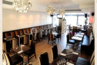 Miniature Location salle Rueil-Malmaison (Hauts-de-Seine) - Restaurant l'Avenue #5 Bar lumineux avec comptoir décoré de bouteilles colorées, entouré de tabourets et d'étagères garnies de bouteilles.