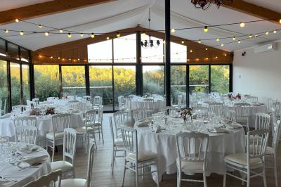 Entrée d'un bâtiment éclairé en soirée, avec des plantes décoratives et des personnes visibles à l'intérieur.