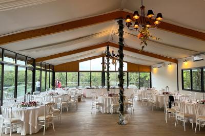 Entrée d'un bâtiment éclairé en soirée, avec des plantes décoratives et des personnes visibles à l'intérieur.