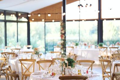 Entrée d'un bâtiment éclairé en soirée, avec des plantes décoratives et des personnes visibles à l'intérieur.