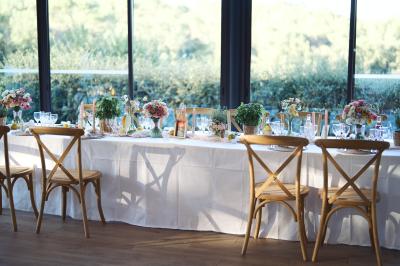 Entrée d'un bâtiment éclairé en soirée, avec des plantes décoratives et des personnes visibles à l'intérieur.