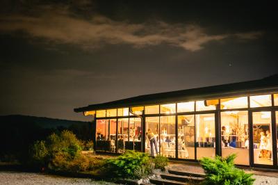 Entrée d'un bâtiment éclairé en soirée, avec des plantes décoratives et des personnes visibles à l'intérieur.