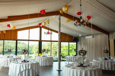 Entrée d'un bâtiment éclairé en soirée, avec des plantes décoratives et des personnes visibles à l'intérieur.