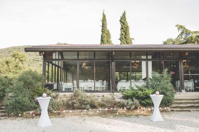 Entrée d'un bâtiment éclairé en soirée, avec des plantes décoratives et des personnes visibles à l'intérieur.