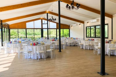 Miniature Location salle Villeneuve-Loubet (Alpes-Maritimes) - Carré des Cavaliers #5 Terrasse en bois aménagée avec tables hautes, parasols et mobilier, entourée de végétation sous un ciel dégagé.