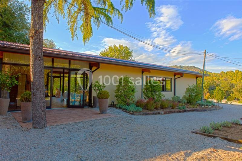 Maison moderne de plain-pied entourée de végétation, avec une terrasse en bois et un jardin aménagé.