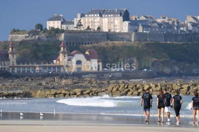 Vue d'une plage à marée basse avec des bouées jaunes et des structures ostréicoles dans une mer calme.