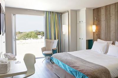 Vue d'une plage à marée basse avec des bouées jaunes et des structures ostréicoles dans une mer calme.