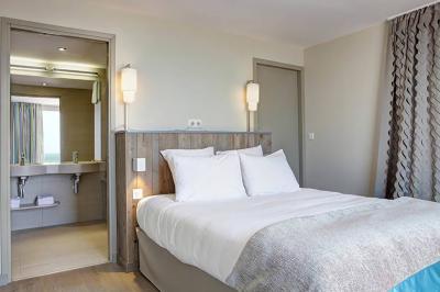 Vue d'une plage à marée basse avec des bouées jaunes et des structures ostréicoles dans une mer calme.