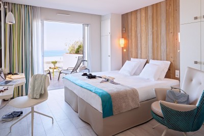 Vue d'une plage à marée basse avec des bouées jaunes et des structures ostréicoles dans une mer calme.