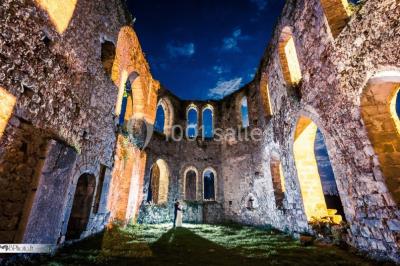 Salle de réception décorée avec des tables rondes, nappes blanches, chandeliers et guirlandes florales suspendues.
