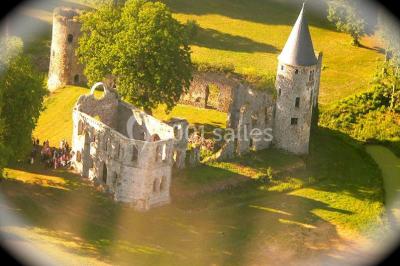 Salle de réception décorée avec des tables rondes, nappes blanches, chandeliers et guirlandes florales suspendues.