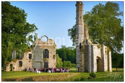 Salle de réception décorée avec des tables rondes, nappes blanches, chandeliers et guirlandes florales suspendues.