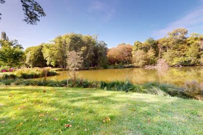 Espace d'attente avec fauteuils noirs, tables basses, escalier en bois courbé et plantes dans un intérieur lumineux.