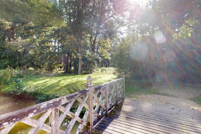 Espace d'attente avec fauteuils noirs, tables basses, escalier en bois courbé et plantes dans un intérieur lumineux.