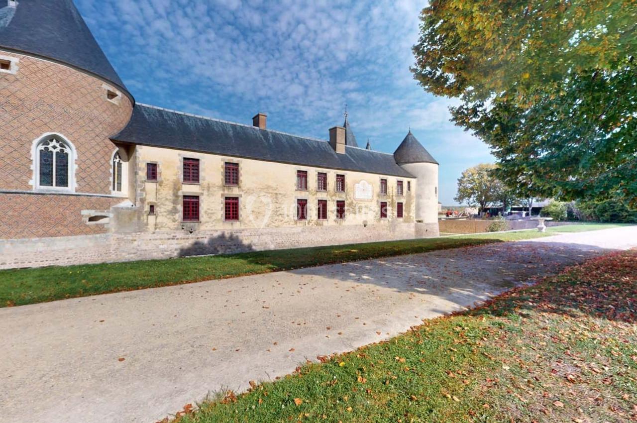 Façade d'un château historique avec tours rondes, chemin en premier plan et arbres aux feuilles d'automne.