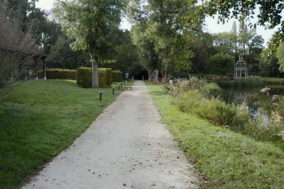 Espace d'attente avec fauteuils noirs, tables basses, escalier en bois courbé et plantes dans un intérieur lumineux.