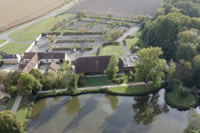 Espace d'attente avec fauteuils noirs, tables basses, escalier en bois courbé et plantes dans un intérieur lumineux.