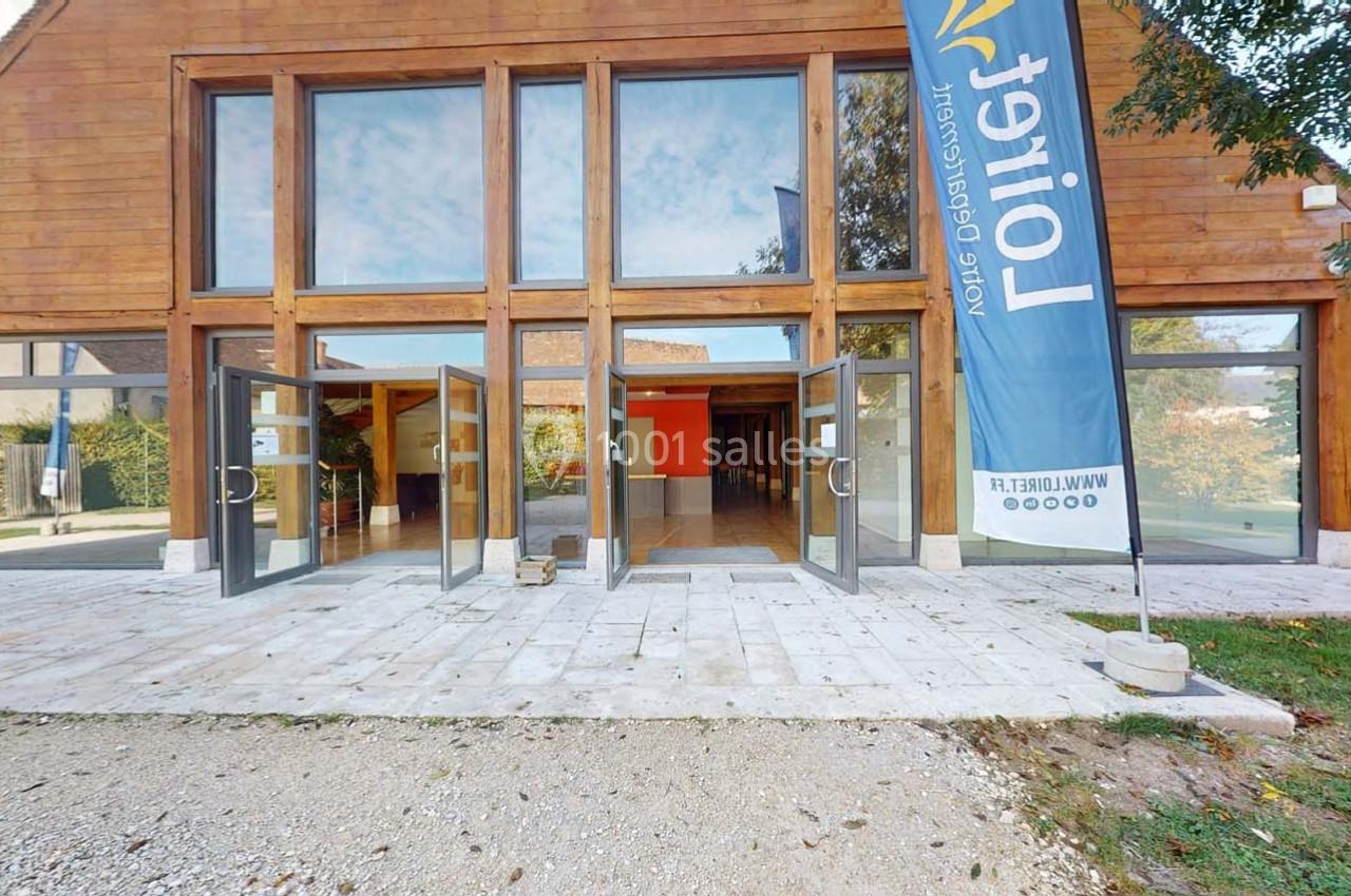 Façade d'un bâtiment en bois avec de grandes baies vitrées ouvertes, une bannière bleue visible à droite.