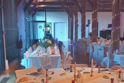 Espace d'attente avec fauteuils noirs, tables basses, escalier en bois courbé et plantes dans un intérieur lumineux.